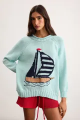 Sweater de punto color marfil con diseño de velero en la parte frontal, cuello con capucha y cordón rojo de ajuste.