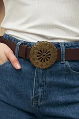 Cinturón negro de poliuretano con hebilla metálica calada con diseño floral y apliques en relieve.