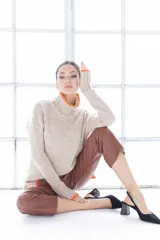 Sweater de punto color beige con cuello alto y ribete naranja en cuello y puños.
