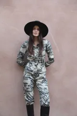 Mono largo de gabardina color beige con estampado de tigres y árboles. Tiene cuello camisero, cierre frontal con botones, cintura elástica y bolsillos laterales.