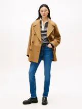 Jean ajustado de talle medio, color azul medio, con efecto desteñido en muslos y costuras, y efecto usado en la parte delantera. Presenta cierre de cremallera con botón y estilo de cinco bolsillos.