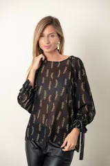 Blusa negra de gasa con estampado de cadenas doradas, escote redondo y mangas largas abullonadas con lazos en los puños.