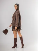 Chaqueta de estilo boho confeccionada en ecocuero agamuzado, con diseño de flecos en el frente, cierre frontal con botones y bolsillos laterales. Presenta un corte holgado y forro interior.