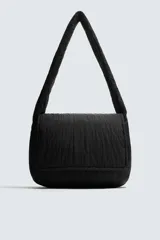 Bolso de hombro confeccionado en tejido técnico acolchado de color negro. Presenta un diseño de solapa con cierre magnético y cremallera, asa de hombro integrada y compartimentos interiores.