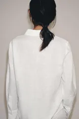 Camisa de lino de corte clásico con cuello solapa, manga larga con puños anchos y cierre frontal con botones.
