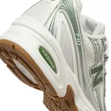 Championes New Balance modelo 740, con diseño técnico en malla blanca y superposiciones plateadas con detalles en verde. Cuenta con entresuela blanca con tecnología ABZORB y suela de goma color caramelo.