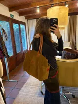 Bolso amplio marrón de gamuza con manijas de cuero, bolsillos laterales con clip, cierre posterior y bolsillo interno.