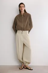 Cazadora tipo bomber color marrón, confeccionada en mezcla de viscosa. Tiene cuello solapa, manga larga, bolsillos de vivo en los laterales y bajo acabado en elástico. Cierre frontal con cremallera metálica.