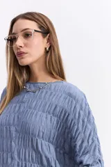 Blusa de manga larga con textura fruncida en toda la prenda, cuello redondo y corte relajado.