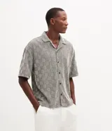 Camisa de manga corta Marfinno con corte boxy, cuello bowling y cierre frontal abotonado. Confeccionada en tejido texturizado con diseño geométrico de cuadros.