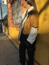 Campera marrón con mangas de corderito color crema y parte inferior de cuero sintético negro con textura de cocodrilo.