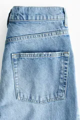 Jean tobillero barrel de tiro alto, confeccionado en denim de algodón rígido color celeste con efecto deslavado. Presenta diseño curvo en las piernas con volumen y tiras finas para atar en los bajos.