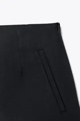 Bermuda negra de tiro alto con bolsillos delanteros de vivo y cierre lateral con cremallera oculta en costura.