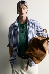 Camisa relaxed fit confeccionada en tejido de algodón, con diseño de rayas verticales en tonos azul y blanco, cuello con botones y manga larga.