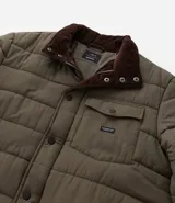 Campera puffer negra con cuello alto, cierre frontal con botones a presión, bolsillos laterales y un bolsillo cargo en el pecho. Presenta un diseño acolchado y forro interior suave.