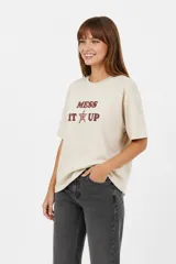 Remera de algodón blanca de manga corta y cuello redondo, con estampa frontal que incluye un corazón rojo y letras con diseño animal print.