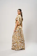 Vestido largo con estampado animal print en tonos camel, blanco y negro. Tiene escote en V, mangas cortas tipo murciélago y tajo frontal. Incluye cinturón ancho de cuero color camel.