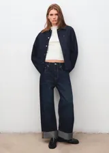 Chaqueta de denim en color azul oscuro, con diseño recto, cuello camisero, cierre frontal de botones metálicos y bolsillos de parche con solapa en el pecho.