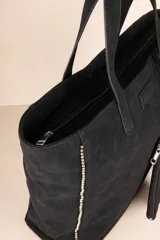 Bolso tipo tote color marrón con tachas plateadas en los bordes y monedero colgante con cierre.