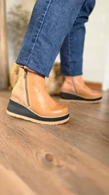 Botinetas de cuero color suela, con diseño de caña baja, doble cierre lateral, talón con textura animal print estilo reptil y suela de plataforma corrida bicolor en negro y suela.