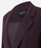 Blazer de sastrería en color negro, de corte alargado y estructura recta. Presenta solapas clásicas, cierre frontal con dos botones, hombros estructurados y mangas largas con detalle de botones en los puños. Incluye bolsillos decorativos y forro interno.