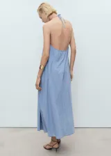 Vestido midi de corte recto y diseño holgado, confeccionado en tejido mezcla de algodón y lino con efecto denim. Presenta cuello de pico con detalle de lazo frontal y tirantes finos ajustables.