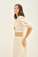 Camisa corta tipo crop top de viscosa con destellos de lurex dorado. Presenta escote en V cruzado con volados, mangas al codo con frunces en los hombros y puños elastizados.