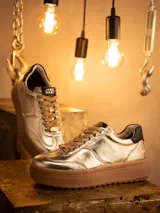 Championes de cuero metalizado en color dorado, con diseño inspirado en C-3PO. Presentan cordones al tono, suela de goma tipo plataforma en color marrón y detalles de marca Star Wars en la lengüeta y el frente.