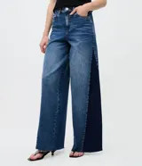 Pantalón wide leg de jean azul, de tiro medio y corte amplio, con detalle de recorte lateral en tono más oscuro y trabillas para cinturón.