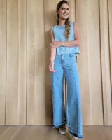 Pantalón de jean de corte recto y tiro alto, con costuras verticales decorativas en el frente y ruedo deshilachado con efecto desgastado.