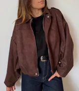 Campera de gamuza color marrón chocolate, con corte oversize, cierre frontal metálico, cuello clásico y hombros caídos.