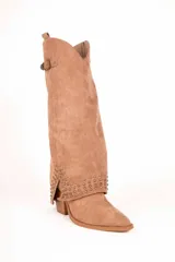 Bota de caña alta estilo slouchy confeccionada en gamuza sintética de color negro, con punta fina y taco bajo. Presenta solapa superior plegada con apliques de tachas metálicas plateadas y una tira con hebilla decorativa en la parte superior de la caña.