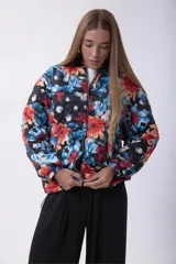 Campera bomber acolchada con cierre frontal, diseño estampado floral multicolor sobre base negra, cuello, puños y ruedo elásticos.