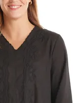 Blusa de algodón color negro con bordados florales al tono. Presenta escote en V con terminación festoneada y mangas largas con puños fruncidos.