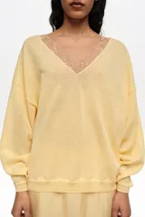 Jersey de corte recto confeccionado en mezcla de lino y algodón, color amarillo, con escote en V pronunciado con detalle de encaje al tono y mangas largas.