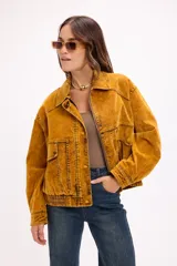 Campera tipo denim oversized en tono ocre lavado, con cierre frontal, bolsillos laterales y detalles de costura marcados. Presenta un diseño de corte holgado con puños y ruedo elásticos.