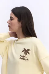 Buzo de algodón color lila, de calce relajado y hombros caídos, con estampa pequeña en el frente que dice "Palm Beach" y una palmera.