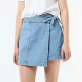 Falda pantalón vaquera de corte cruzado en color azul claro, con detalle de lazo en la cintura.