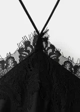 Vestido largo lencero de satén negro, con cuello halter, tirantes finos, detalles de encaje en el escote y en el bajo asimétrico.