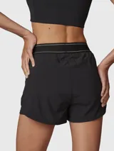 Short deportivo 2 en 1 de color negro, con short interior ajustado y short exterior holgado. Presenta una cintura elástica ancha con detalle de líneas blancas y logo, además de bolsillos laterales invisibles.