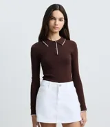 Blusa de punto ajustada color marrón, con cuello polo y cierre frontal con botones. Presenta mangas largas con puños y cuello con detalle de borde en color blanco contrastante.
