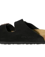 Sandalias tipo zueco marca Rivaro, confeccionadas en cuero gamuzado negro con dos tiras ajustables con hebillas metálicas. Presentan una plantilla anatómica de corcho y látex, y suela de goma antideslizante.