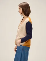 Saco tipo cardigan de tejido de punto con diseño de bloques de color en tonos beige, mostaza y azul marino. Presenta cuello en V, cierre frontal abierto y mangas largas.