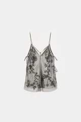 Top de tul con escote en pico y tirantes finos. Presenta bordados florales con aplicación de lentejuelas y laterales ajustables mediante lazadas.