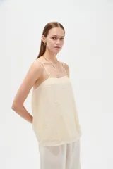 Musculosa de poliéster color marfil, con tirantes finos regulables, cuello cuadrado y diseño holgado, decorada con bordados de estrellas.