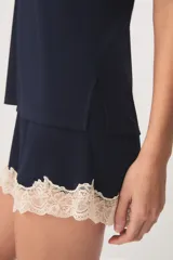 Pijama de dos piezas color verde menta, confeccionado en poliamida y elastano. Incluye una musculosa con tirantes finos y detalles de encaje beige en el escote, y un short con cintura elástica, pequeño lazo decorativo y apliques de encaje en los ruedos.