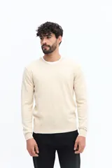 Sweater de punto color gris melange, con escote en V, manga larga y logo bordado en el pecho. Presenta puños y ruedo acanalados.