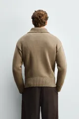 Chaqueta de punto de corte relajado, color marrón, con cuello subido, manga larga y cierre frontal de botones. Presenta acabados en rib en puños y ruedo.