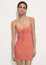 Vestido corto de tirantes finos dobles, con diseño recto y escote de pico. Presenta un estampado de cuadros en tonos naranja y rosado, con un lazo decorativo en el centro del pecho.