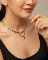 Collar dorado con cadena de eslabones alargados y dije central con forma de corazón estilizado, con la inscripción "UND & 50" en la parte inferior.